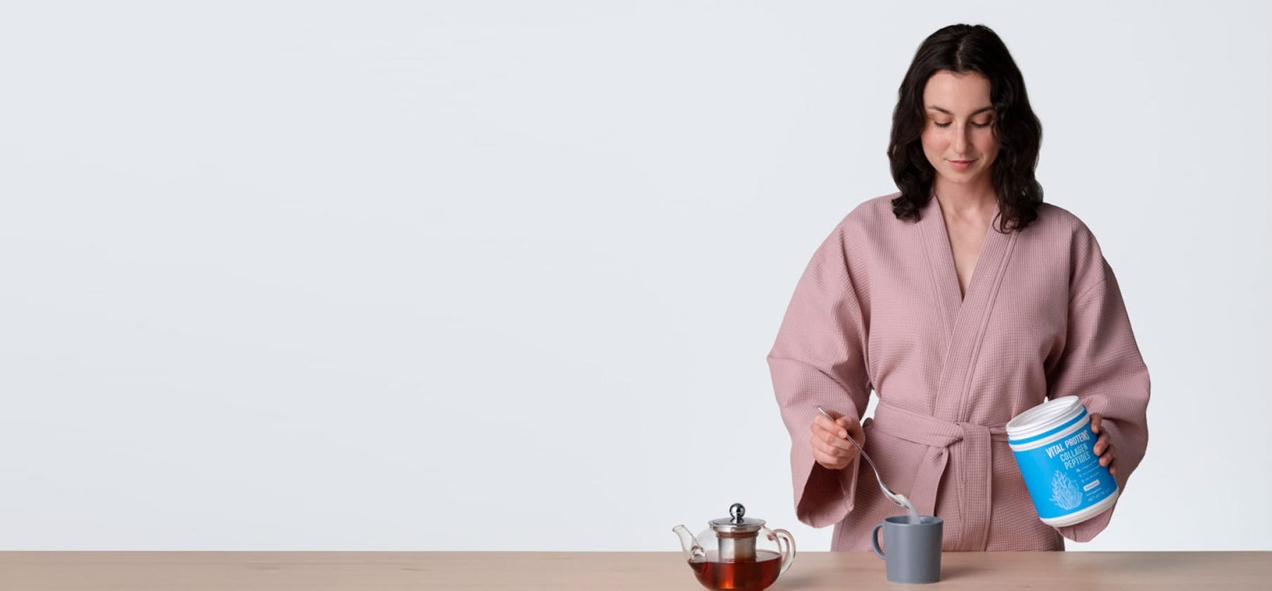 A cup of tea with collagen powder being added, highlighting the preparation of a nutritious drink