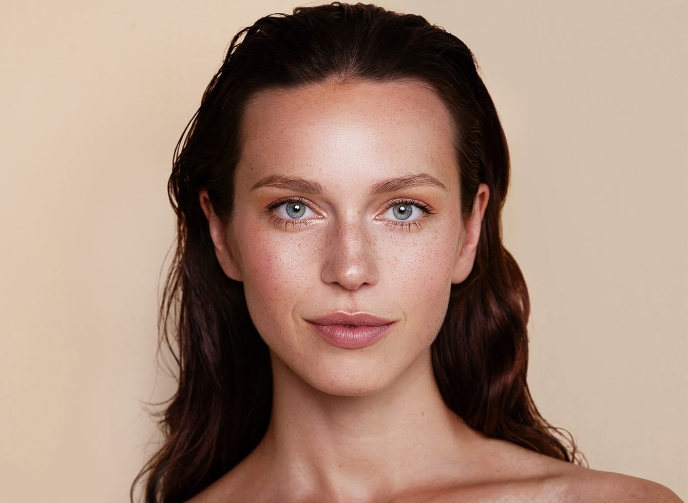A close-up of a woman using hyaluronic acid, emphasizing her glowing skin